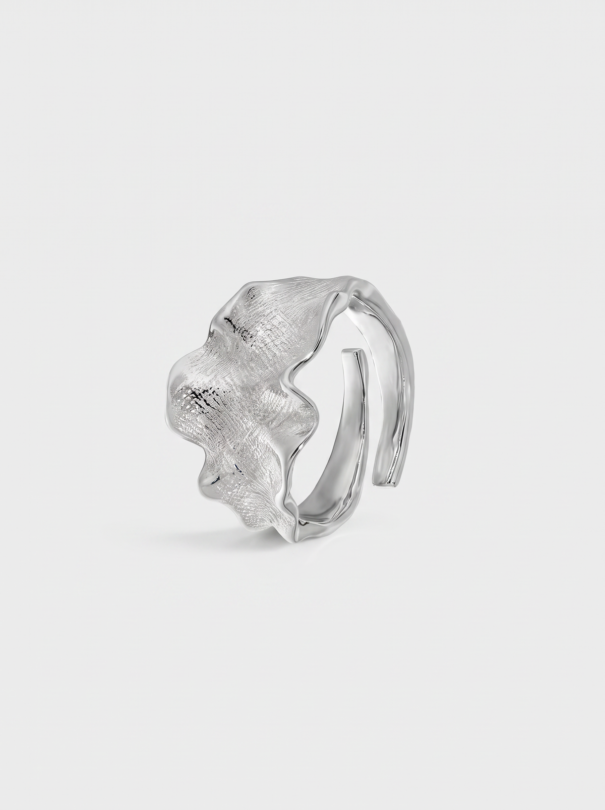 A textured silver ring with a wavy, organic shape and a polished inner band, shown on a light gray background.